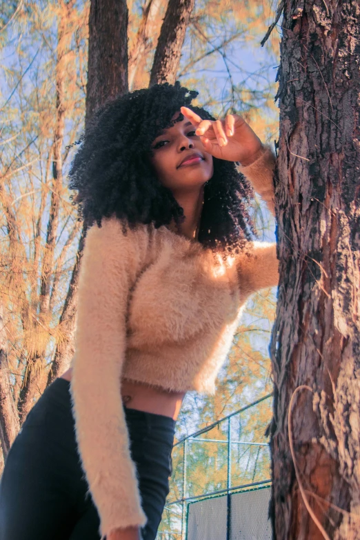 woman with afro standing near tree in wooded area