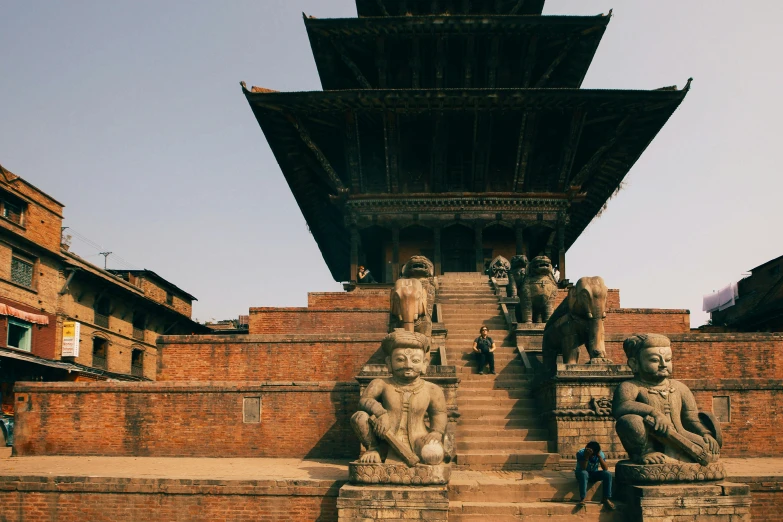 three stone sculptures on some steps with sky in background