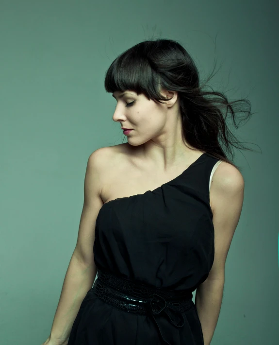 a woman wearing a black dress standing in a studio