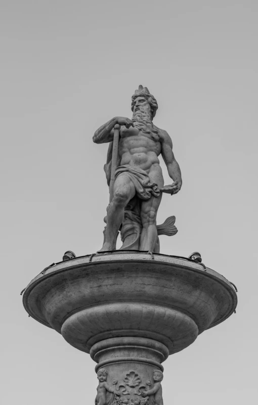 a very tall statue of a male standing on top of a pole