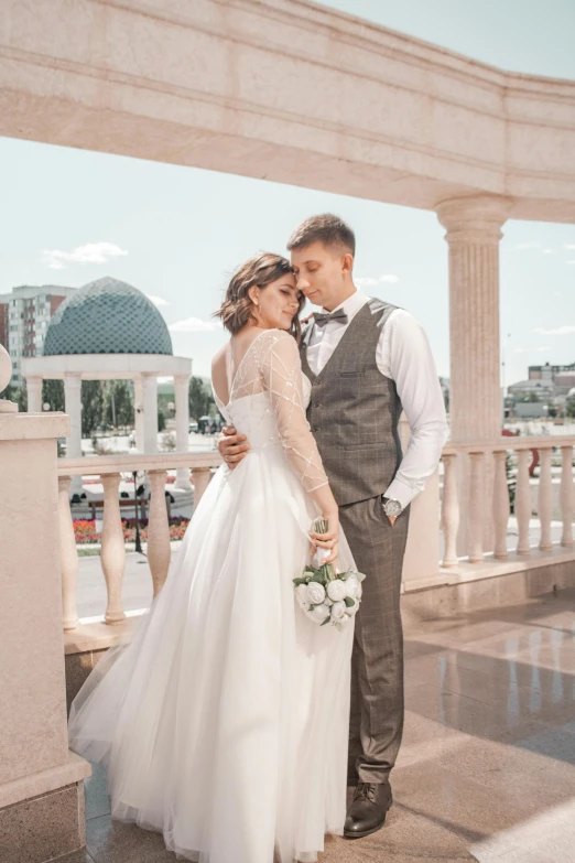 a bride and groom stand in front of a white arch, posing for a pograph