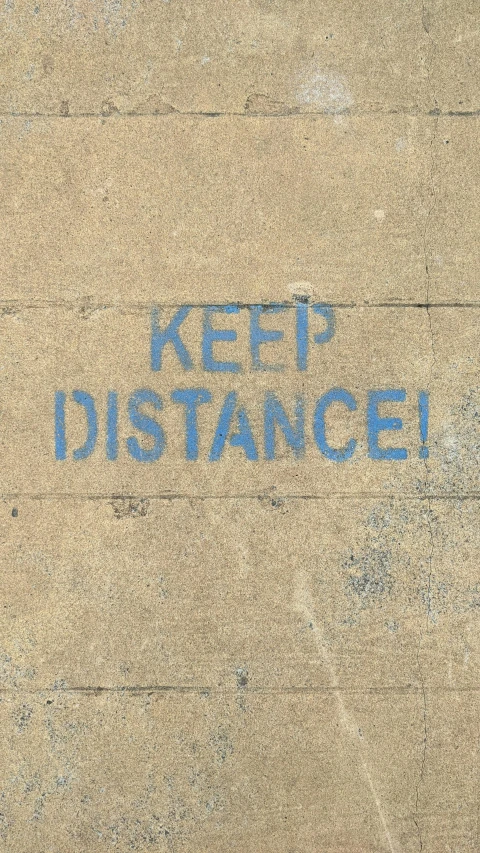 a stop sign painted with blue writing that reads keep distance