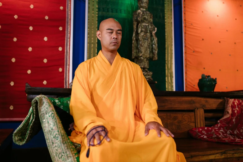 a monk is sitting on a chair next to the wall