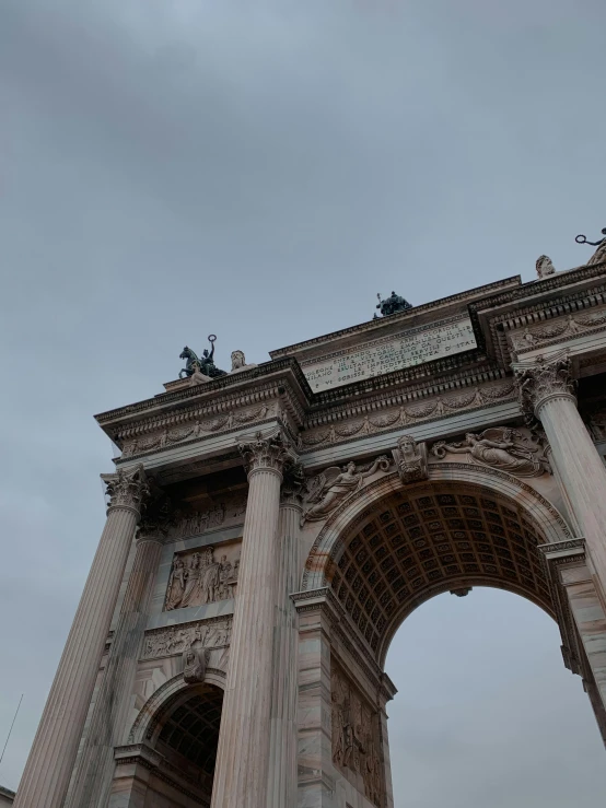 the arch is stone and white with statues on top