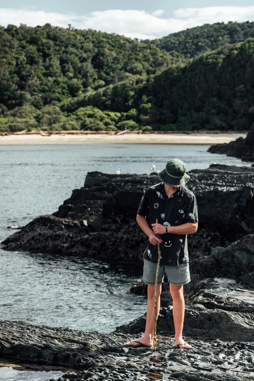 man in hat standing by the sea and holding a camera