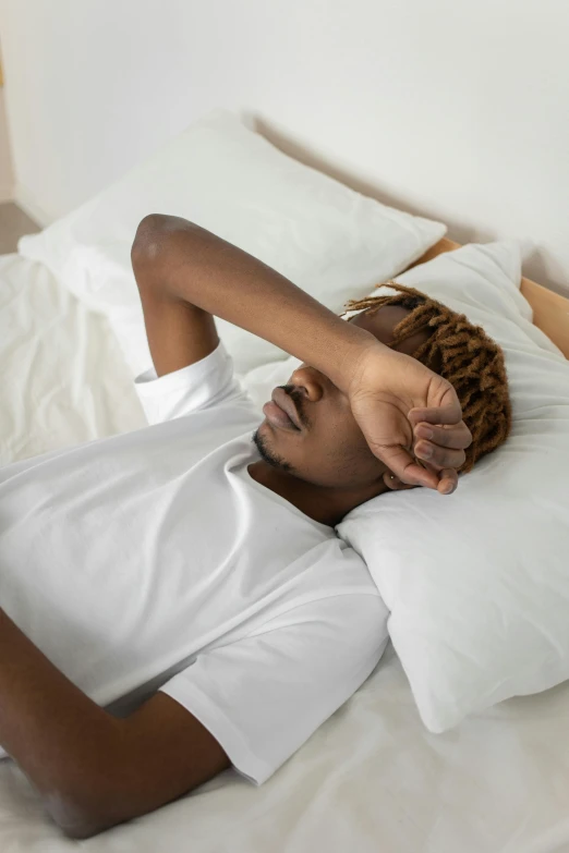 a man laying in bed with his head under the covers