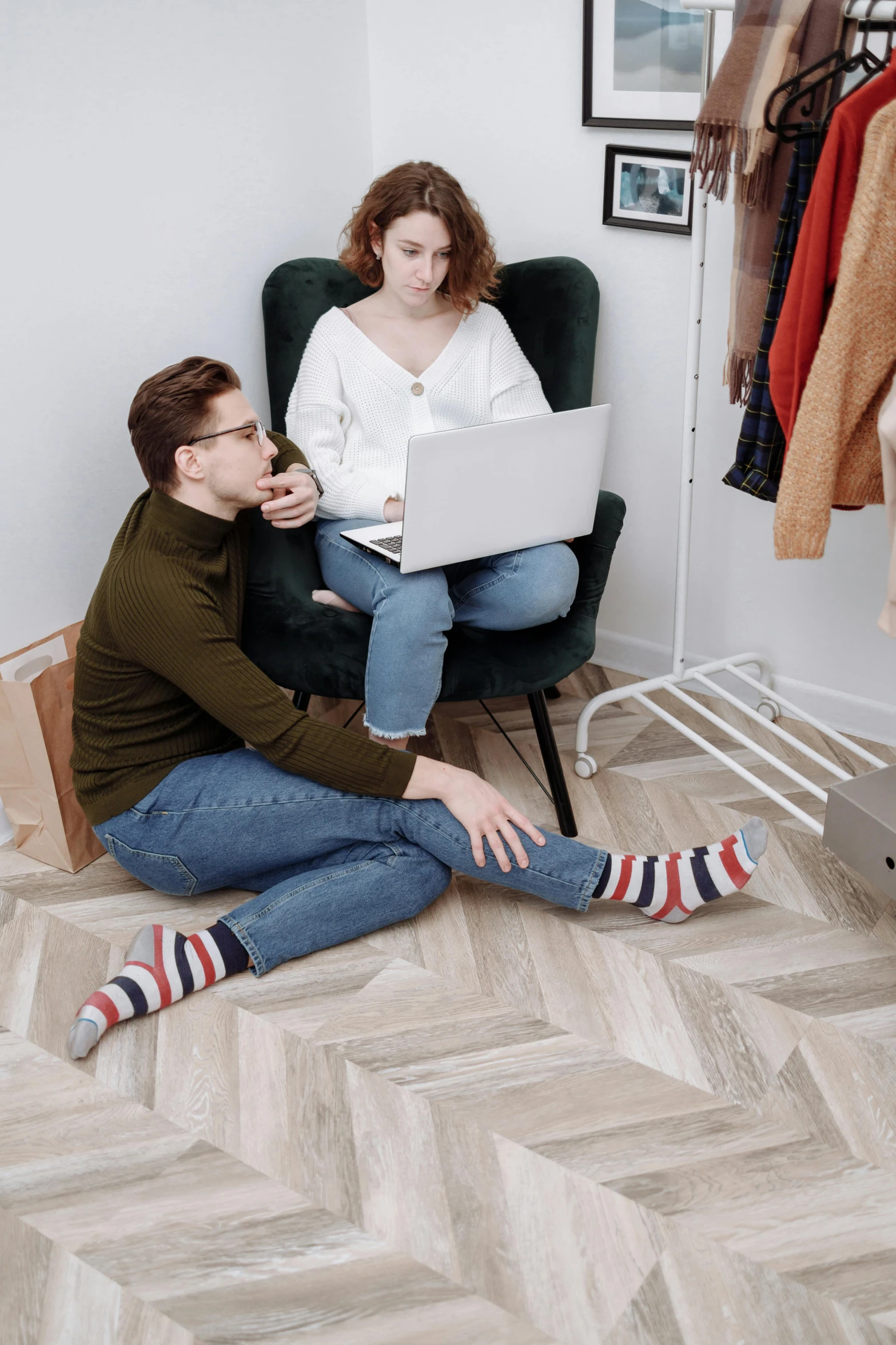 a couple looking at laptop computers while sitting in a chair