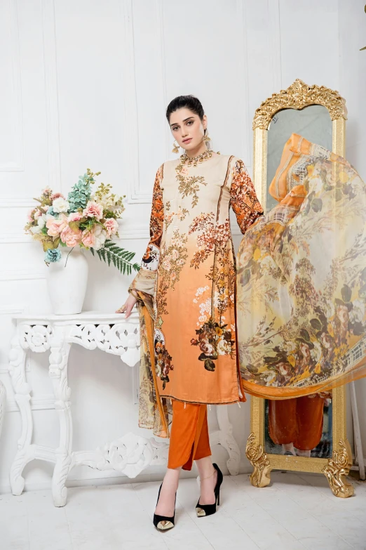 a woman stands in a dress wearing an orange floral pattern