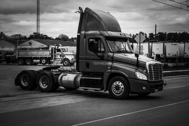 a semi truck driving down the road in black and white