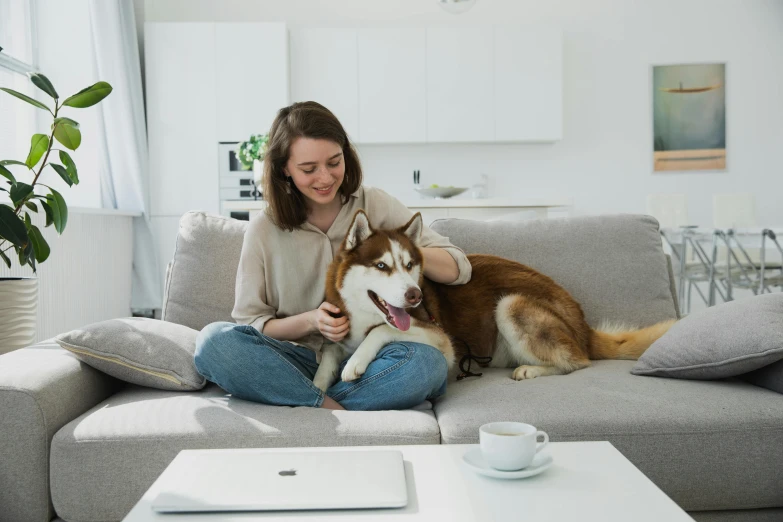 woman sitting on couch with large dog in living room