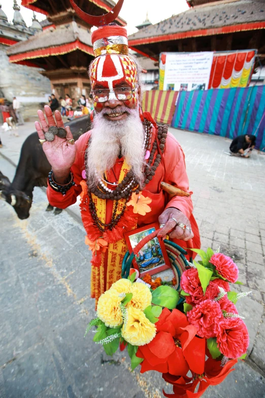 a man in an orange outfit holding flowers on a street