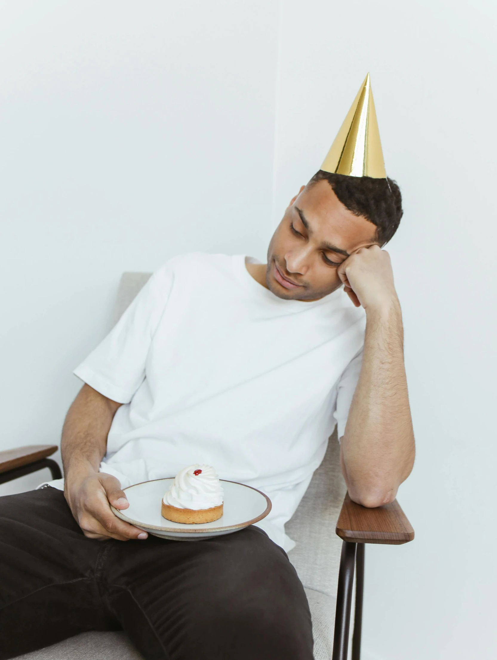 a man sits and looks down while eating cake