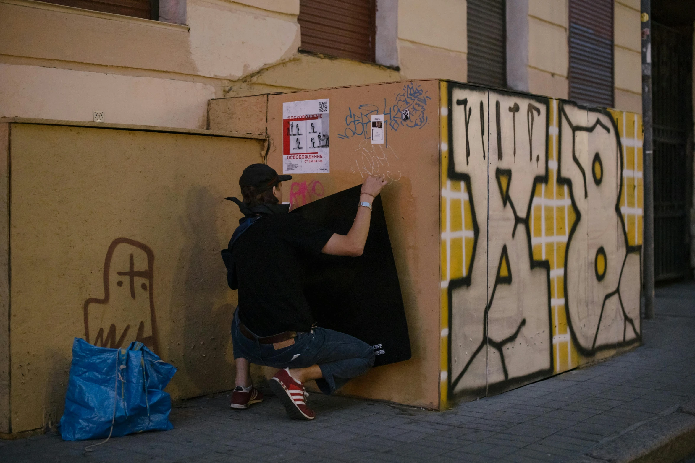 a man leaning up against a wall with a wall that has graffiti on it