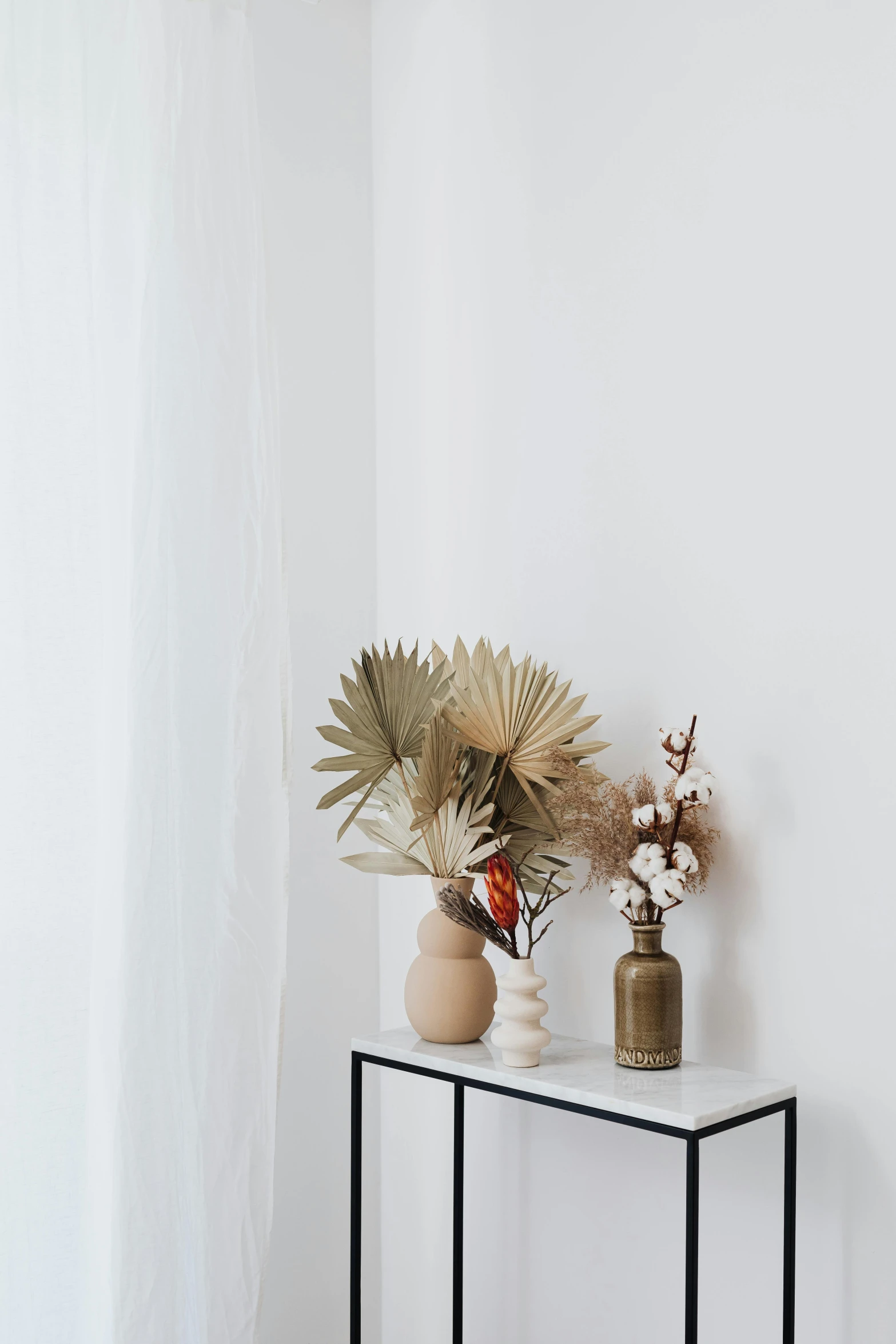 three vases with flowers on a small table