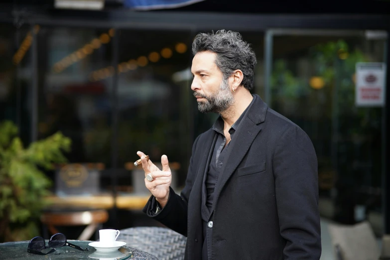 a man holding his finger while standing next to a table