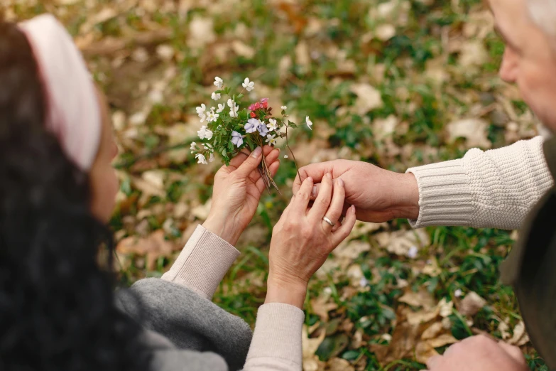 someone putting some flowers on top of another woman's hand