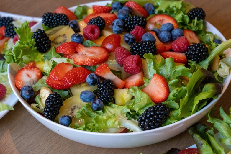 a big bowl of salad with fruit on it