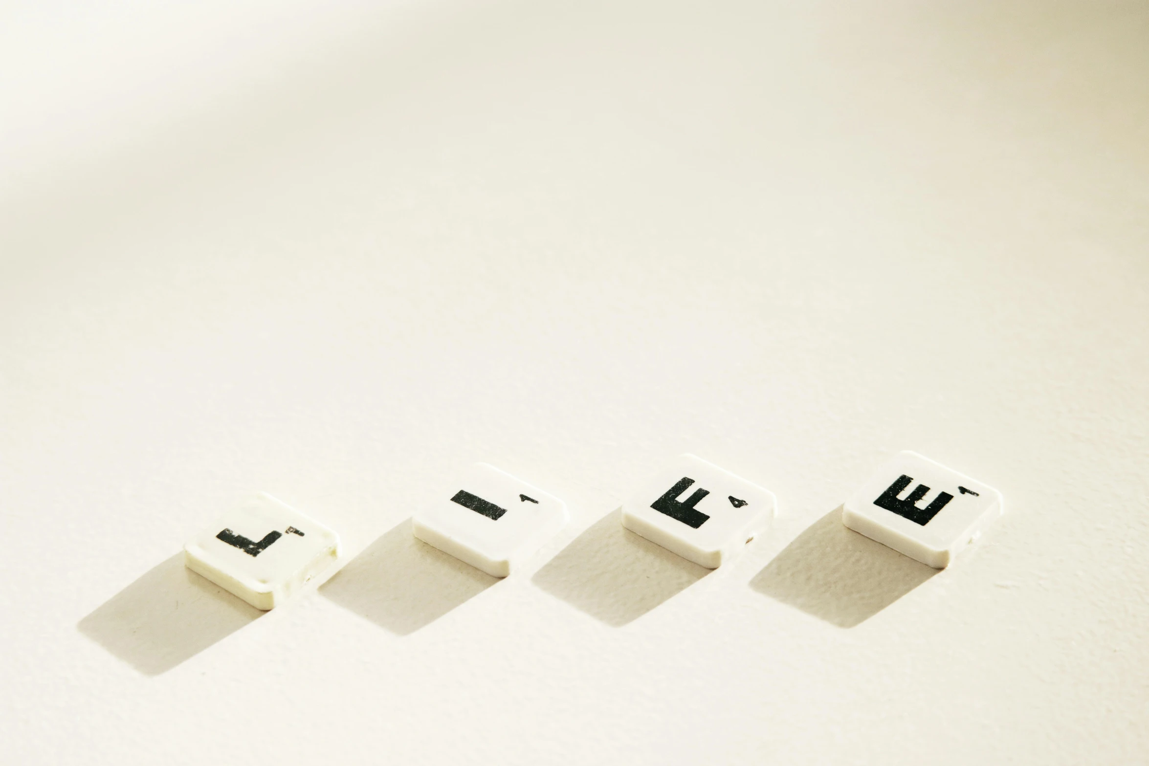 three white cubes with a black letter on one and three letters in the middle