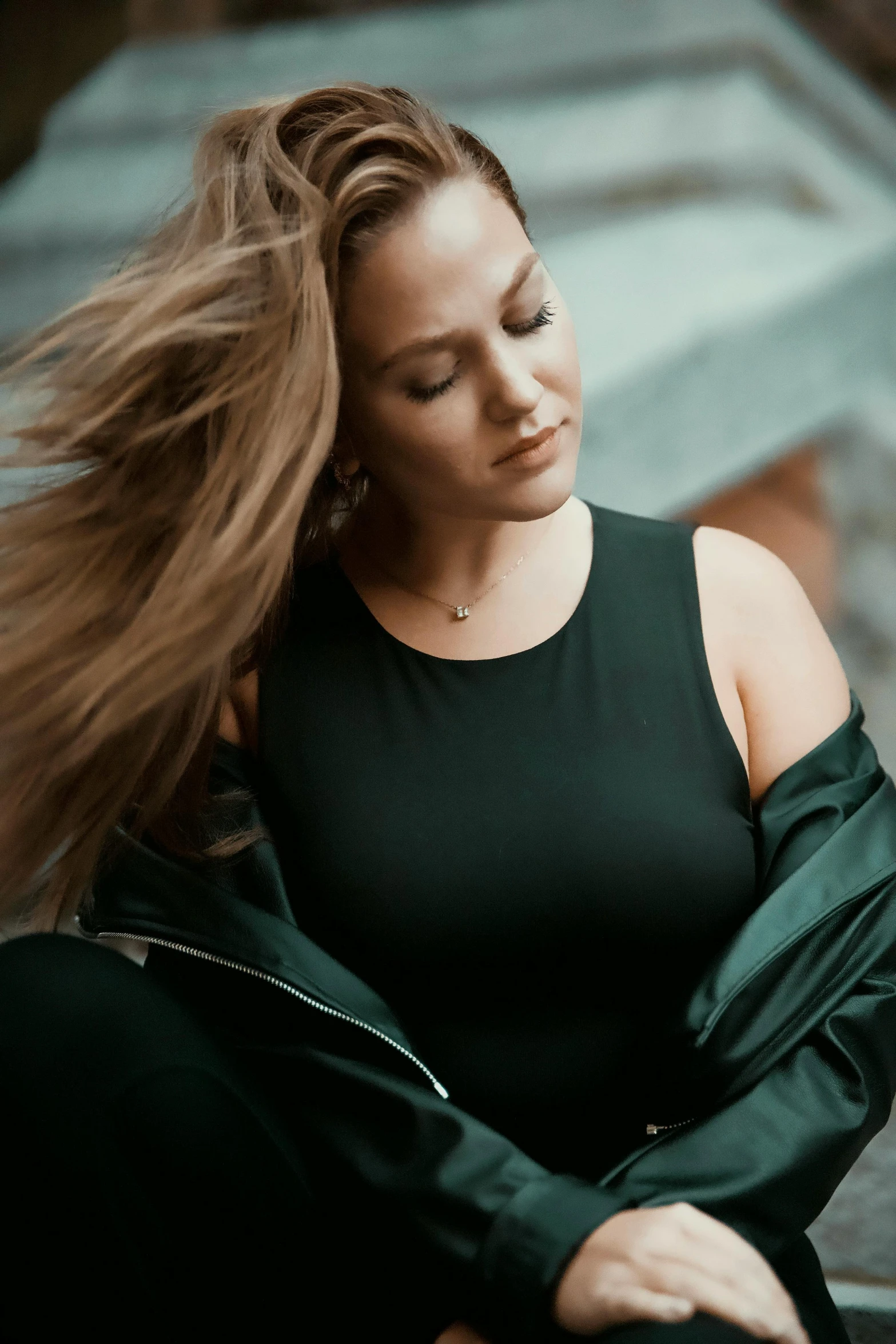 a woman sitting on stairs with her hair flying in the wind