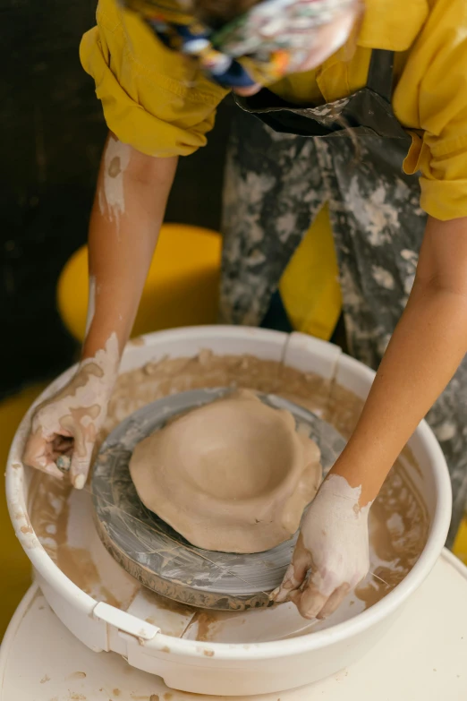 a young person makes pots on an ancient pottery