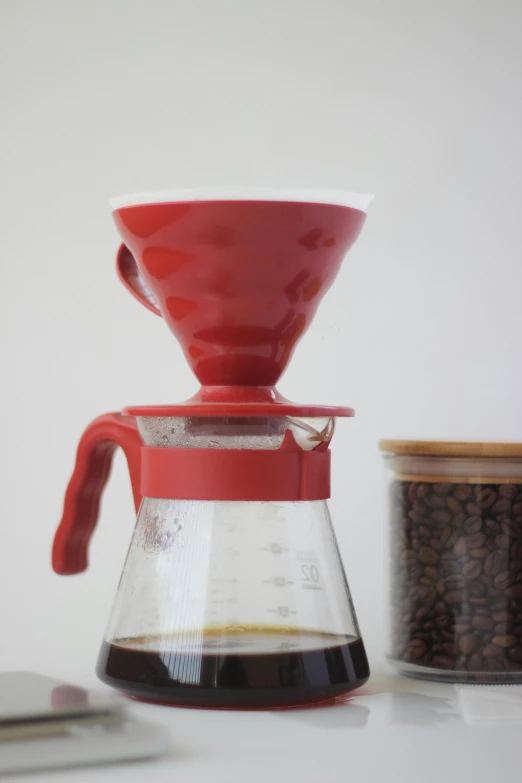 a red coffee pot is next to a glass teapot