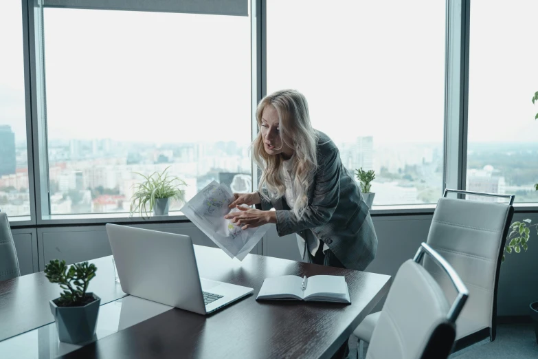 a woman in a suit is sitting at a table looking at a newspaper