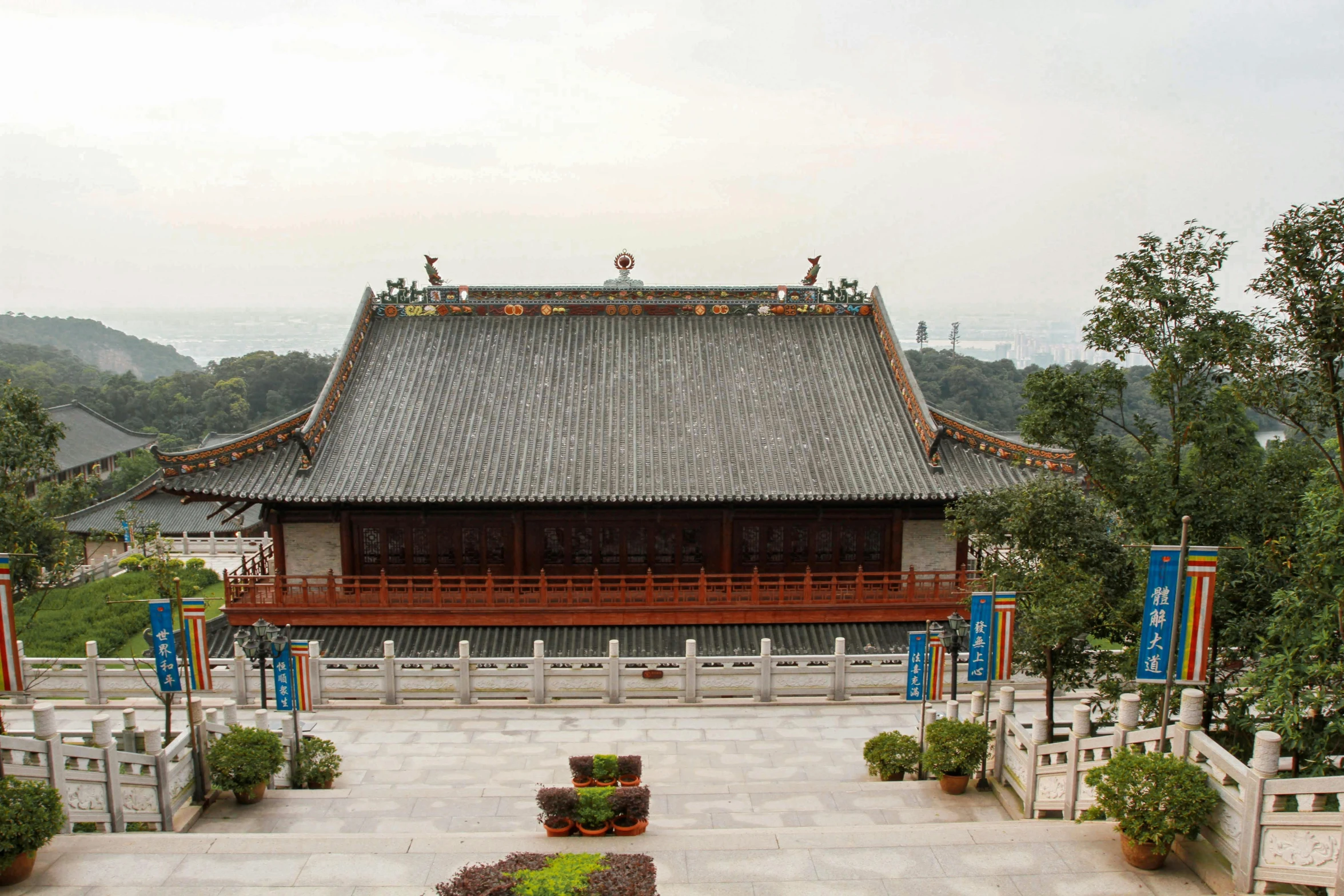 an asian style building that has a large lawn and a pagoda with some bushes in front