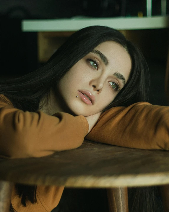 a person sitting at a wooden table with her head resting on the top