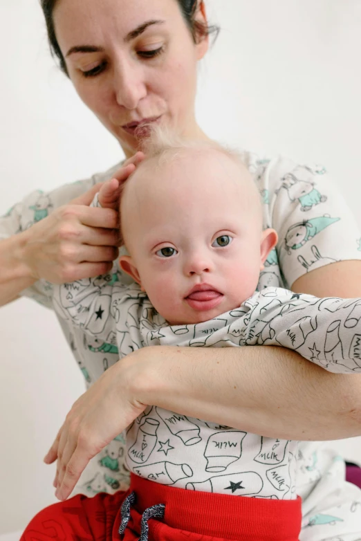 a woman holds a child's hand while he puts it on her