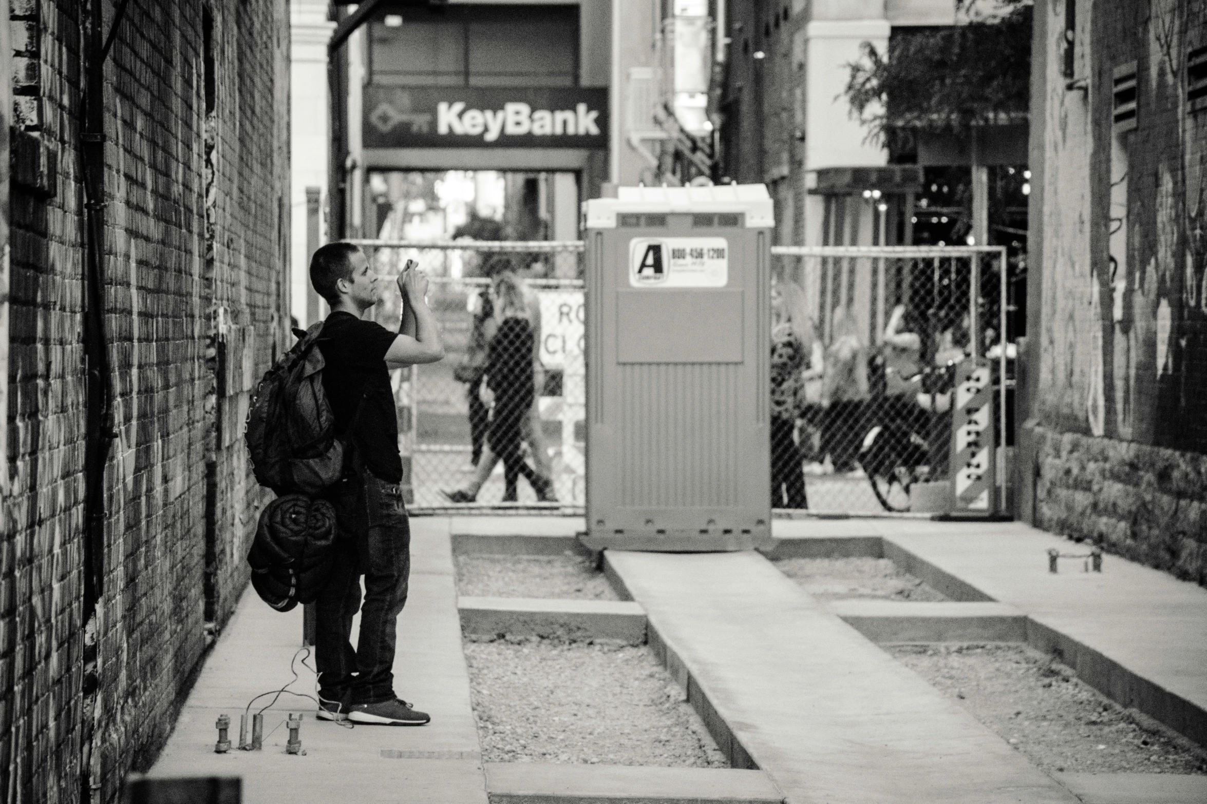 a man with a backpack walks up an alleyway