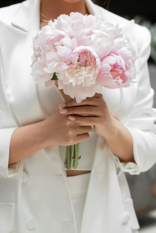 a woman in white jacket holding flowers and a bouquet