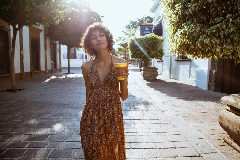 woman drinking a drink standing on a brick sidewalk