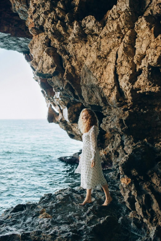 woman standing on rocks next to water