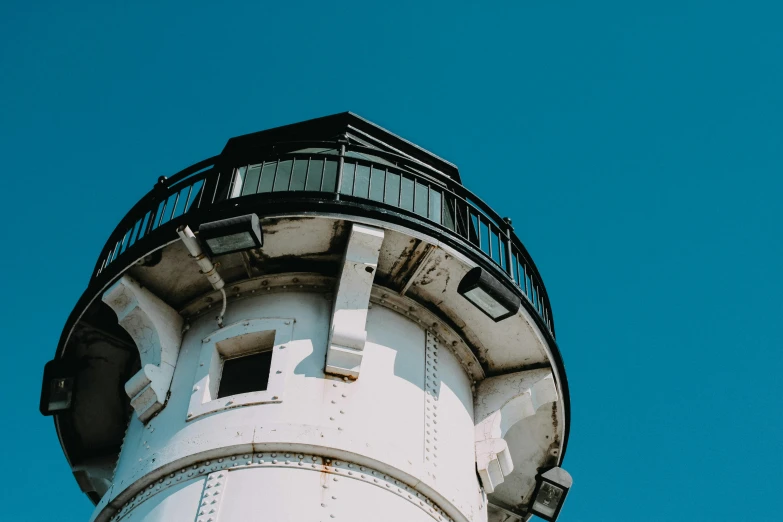 the top of a white lighthouse against a blue sky