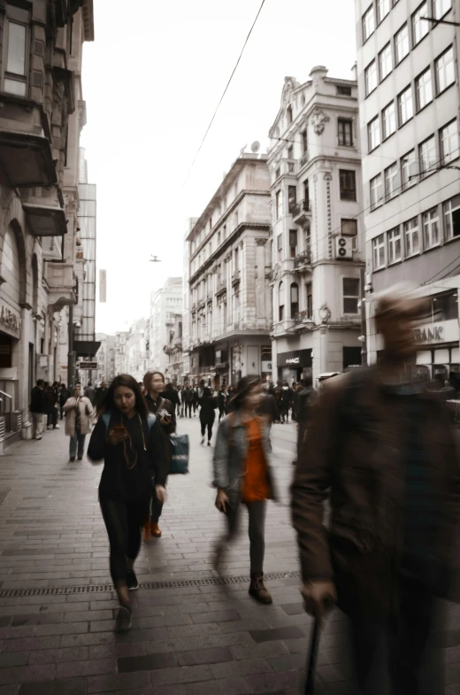 people walk down a city street near a crowd