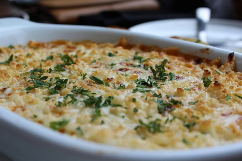 a casserole dish with vegetables and cheese with a spoon