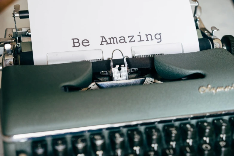 an old fashioned typewriter displaying the word be amazing
