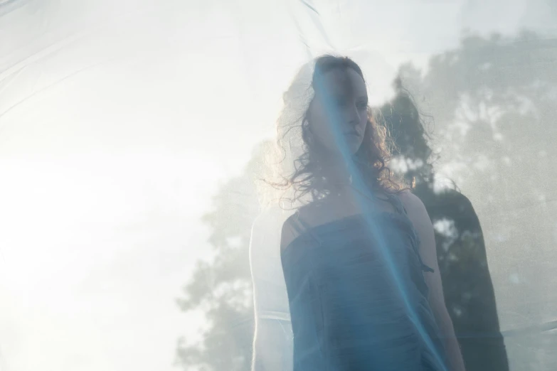 a woman's shadow on a sheet in front of trees