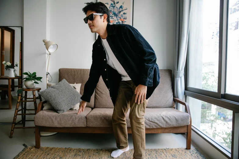 a man is standing near a couch wearing white tennis shoes