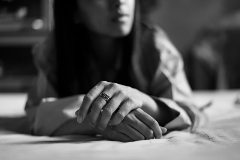 a young woman laying on top of a bed holding a ring