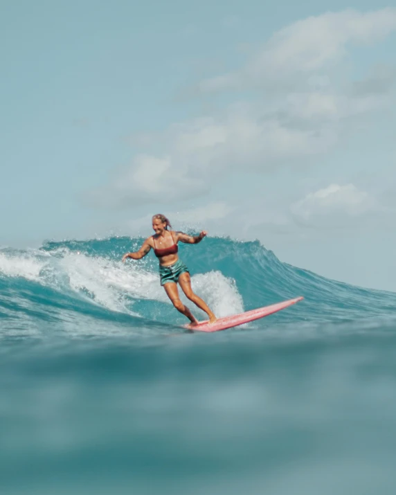 a man riding a wave on top of a pink surfboard