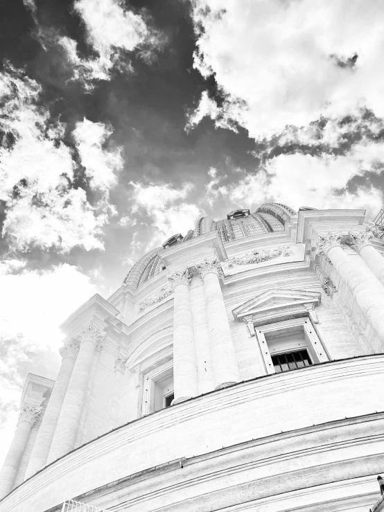 black and white pograph of a tall building with clouds in the background