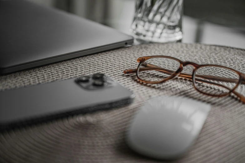 the glasses, mouse and cellphone are on the table next to the glass