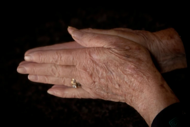 a woman's hand with gold engagement ring and small diamond on her left finger