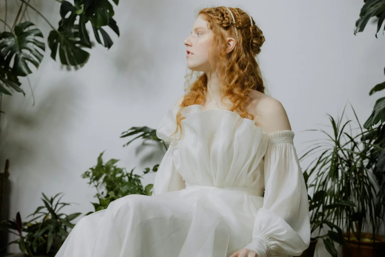 a beautiful redhead woman sitting down in a white dress