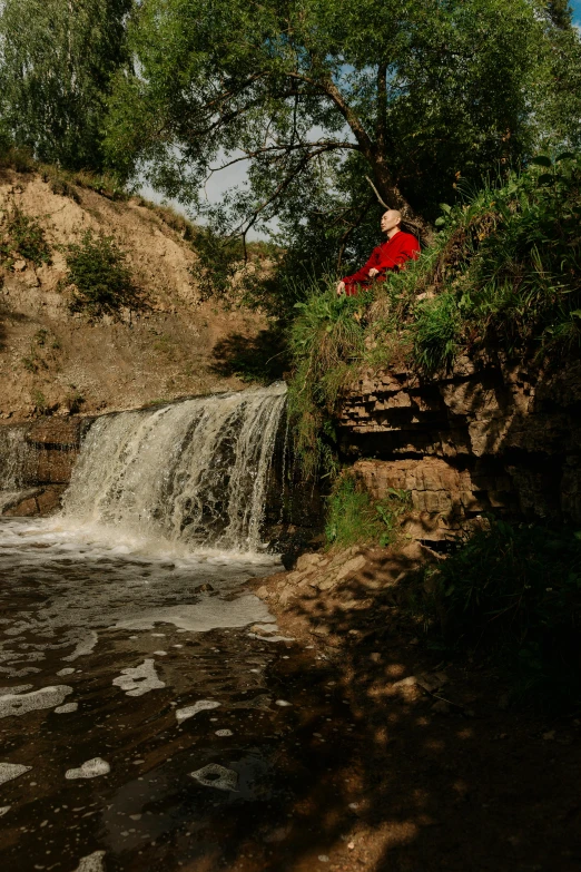 a person on a rope suspended over a small waterfall