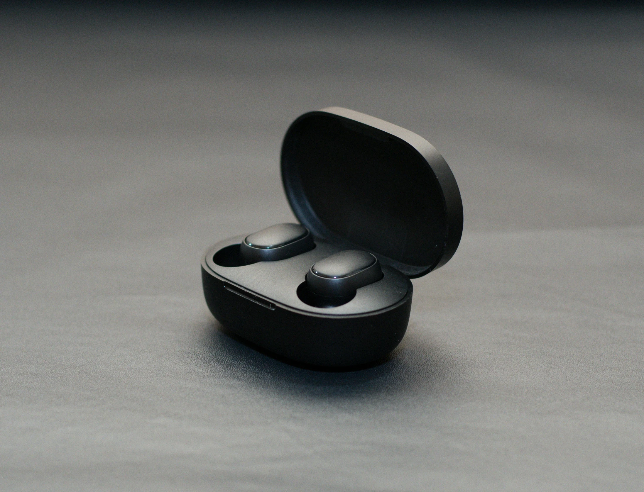 a black earphone and case sitting on the ground