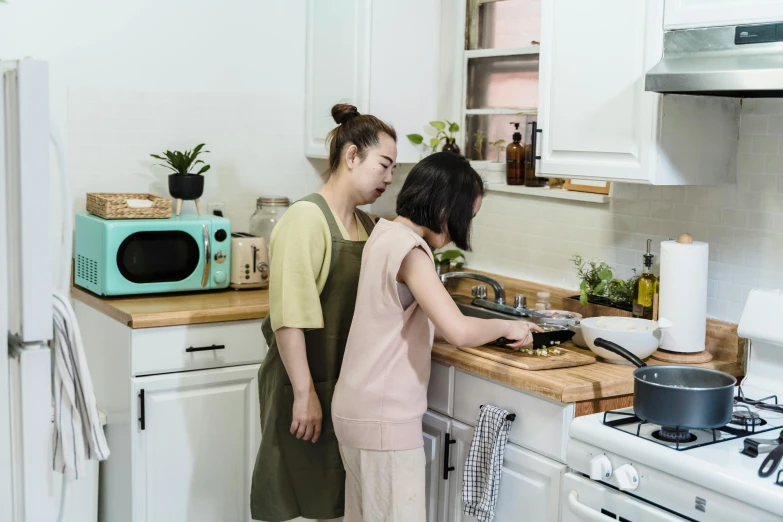 two young people are in a kitchen preparing food