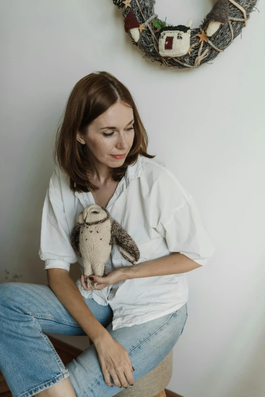 a woman sitting down with her arm over an owl