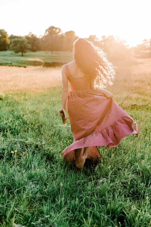 a woman in a dress is running through a grassy field